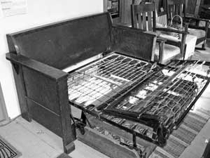 A 1920s Mission-style sofa bed, partially unfolded.