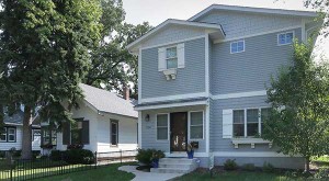 A new infill house looms next to a smaller vintage home.