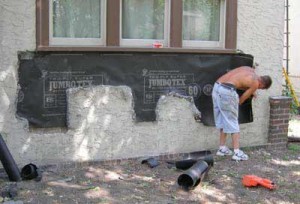 A worker covers the wall’s substructure with tarpaper.